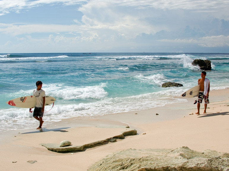 Surfers at Uluwatu beach, Bali, Indonesia.